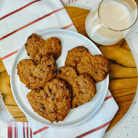 PB2 Pantry Chocolate Chip Cookies made into hearts on a plate with a glass of milk next to them