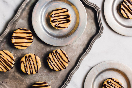 Mini peanut butter cheesecake bites with chocolate glaze drizzled over.